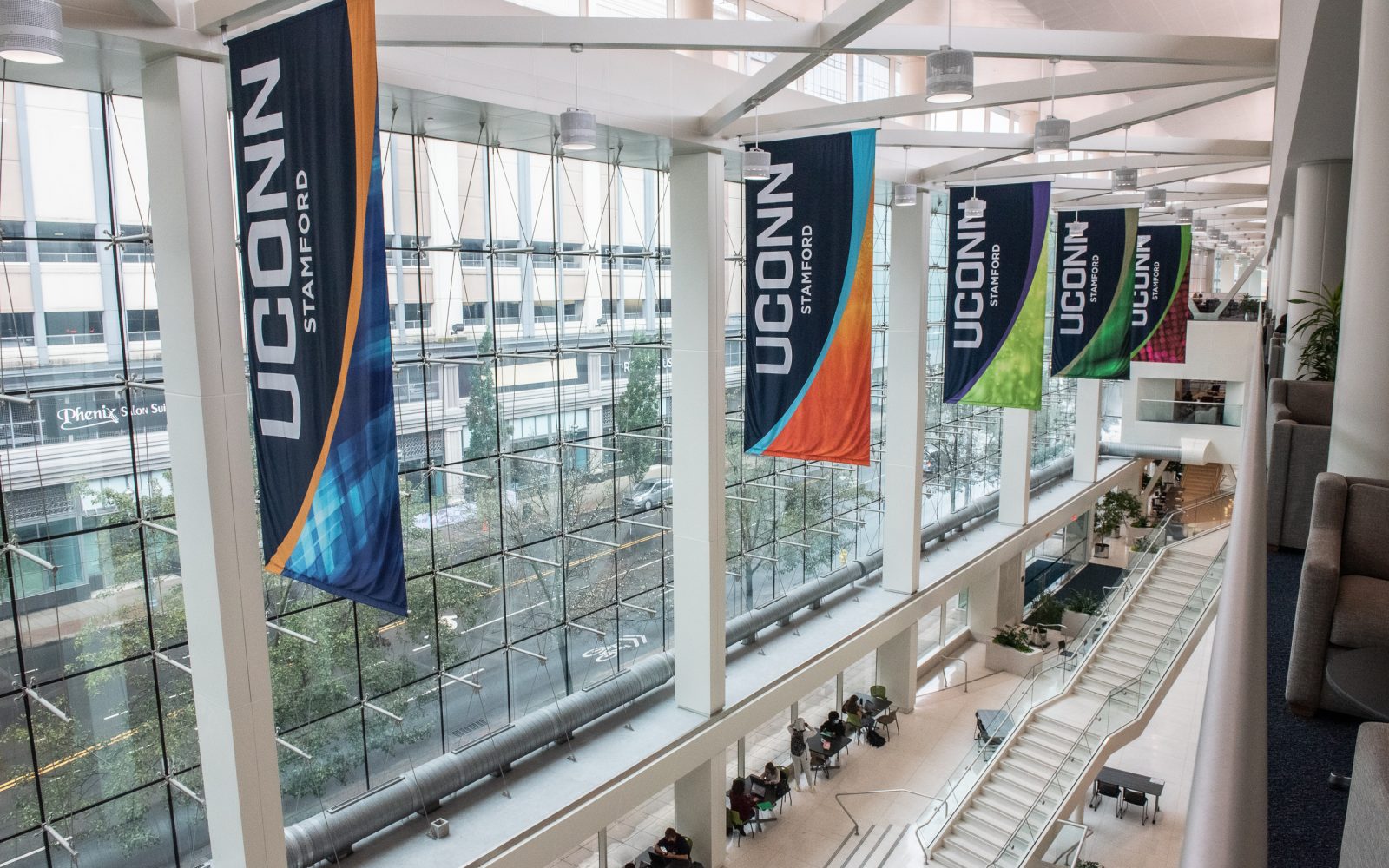 Stamford Building - Flags UConn, Stamford flags in different colors along the ceiling of a large building.